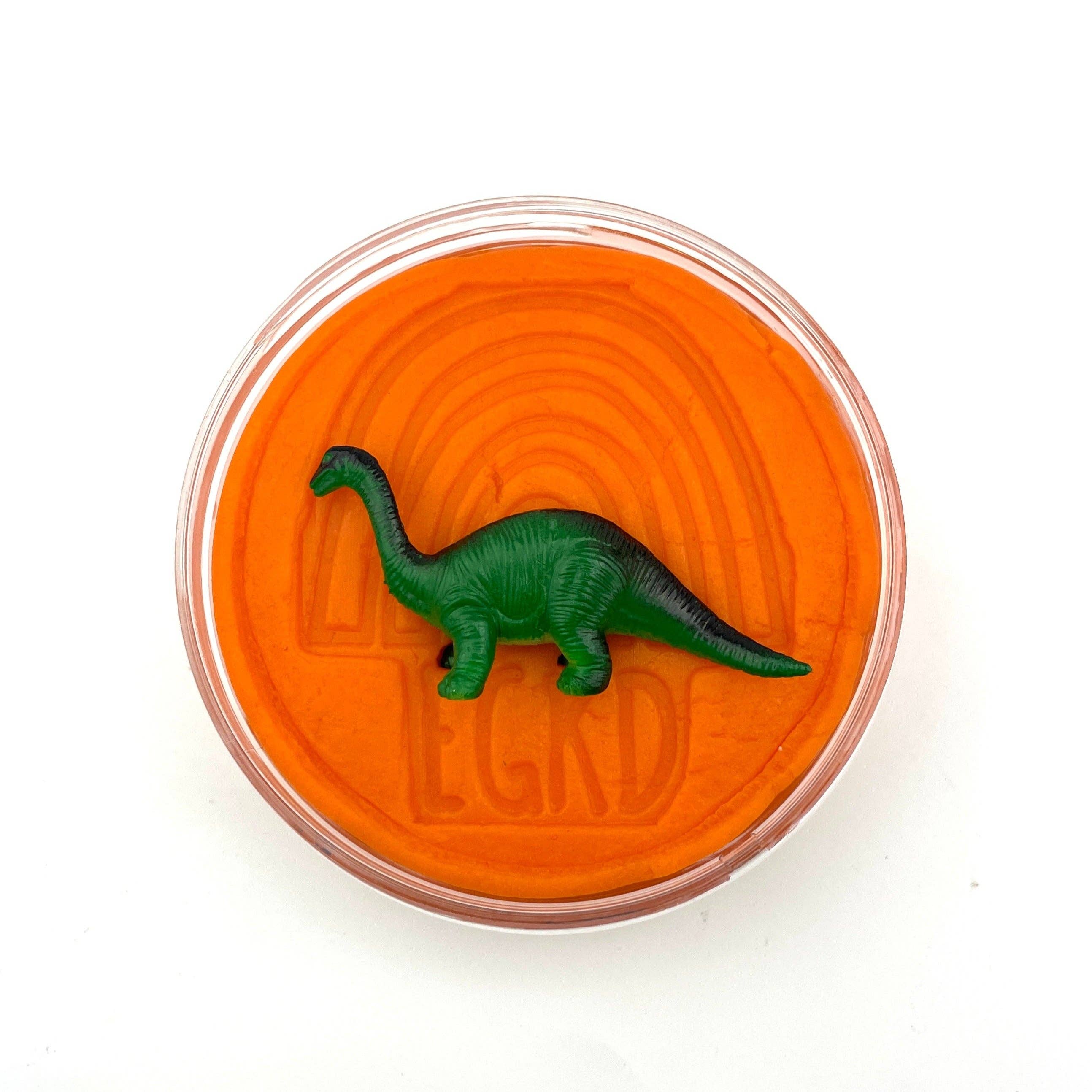 Green dinosaur toy inside an orange container with 'LEGO' branding on a white background