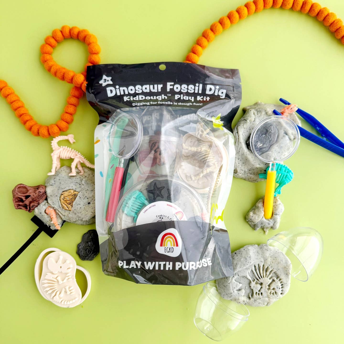 Dinosaur fossil dig play kit with tools and toys on a green background