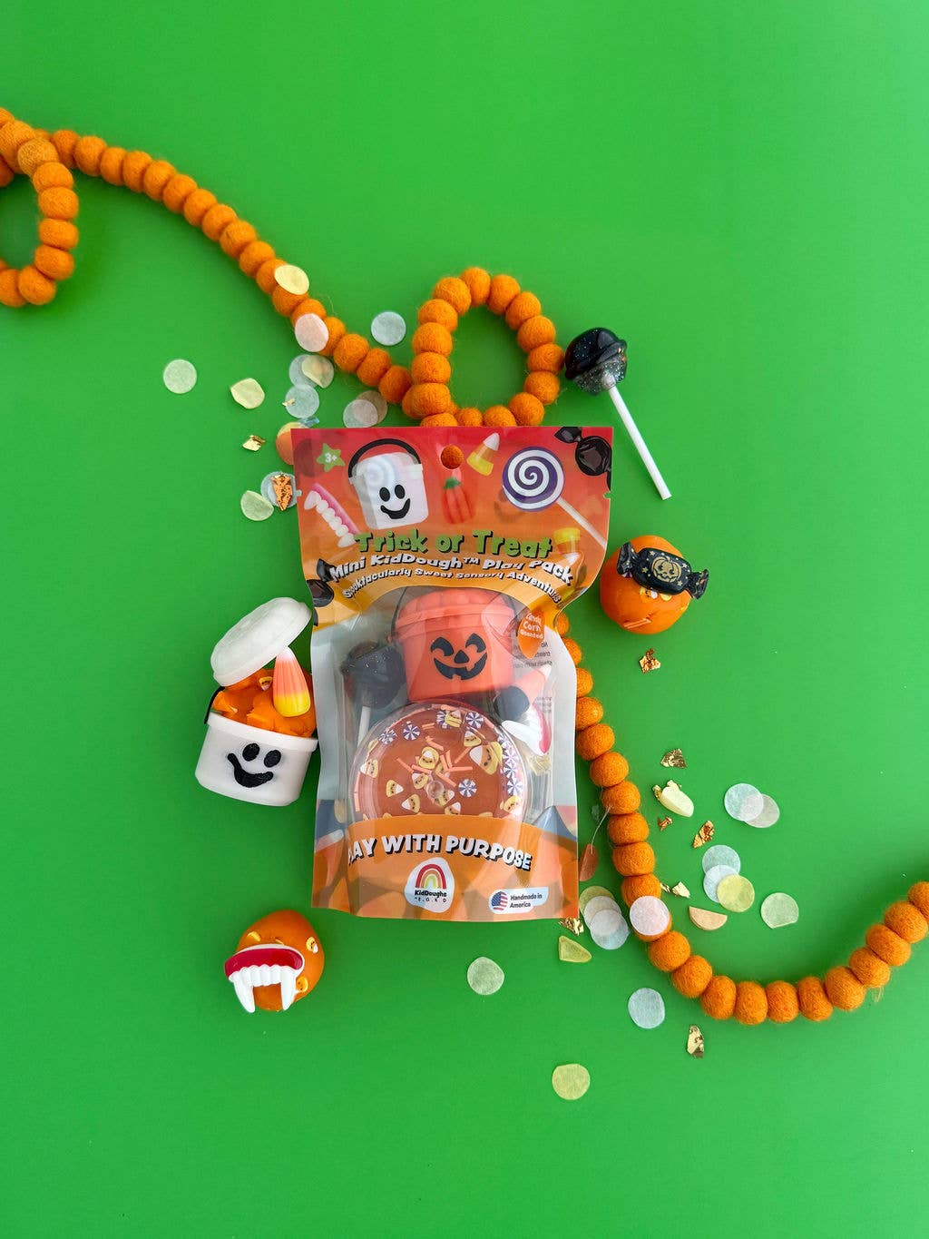Halloween-themed product with candy and confetti on a green background
