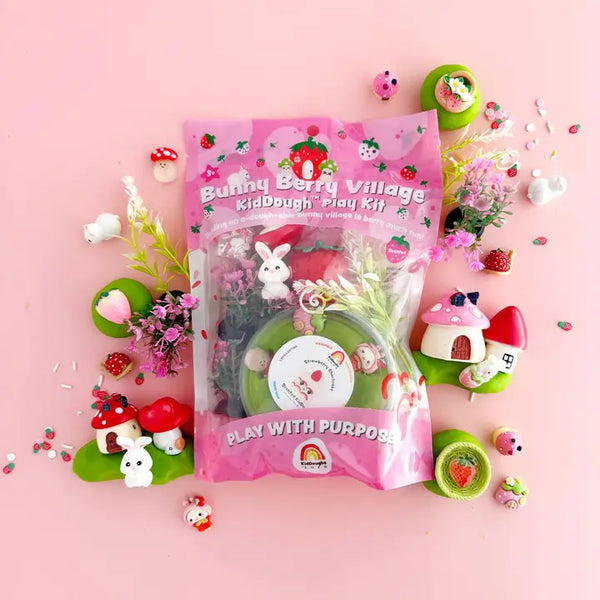 Packaging of Bunny Berry Village KidDough Play Kit with various playful accessories like bunnies, mushrooms, and houses displayed around.
