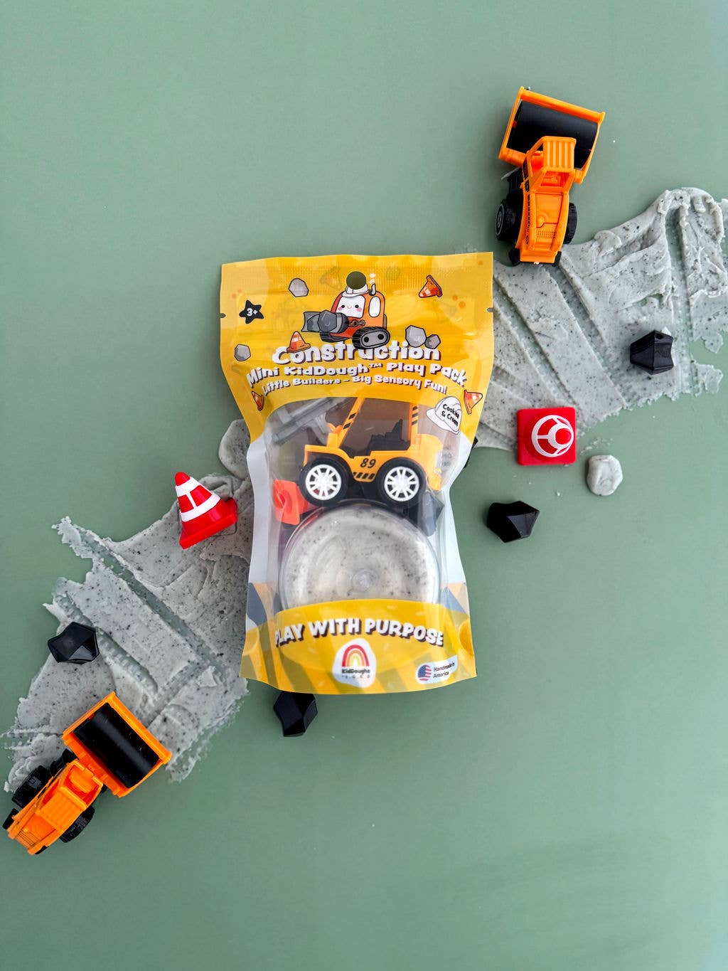 Play dough package with toy trucks and construction elements on a green background