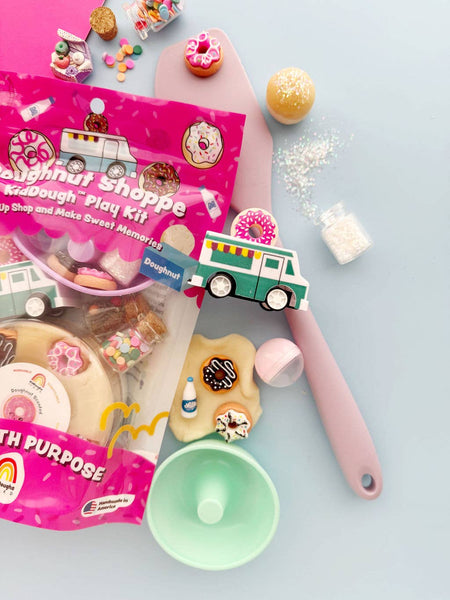 Doughnut-themed play kit with utensils and dough on a light blue background