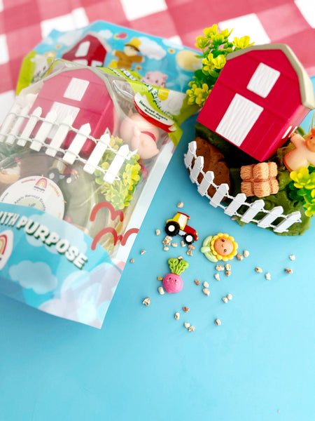 Toy farm set with a red barn, fence, and animals on a blue background.