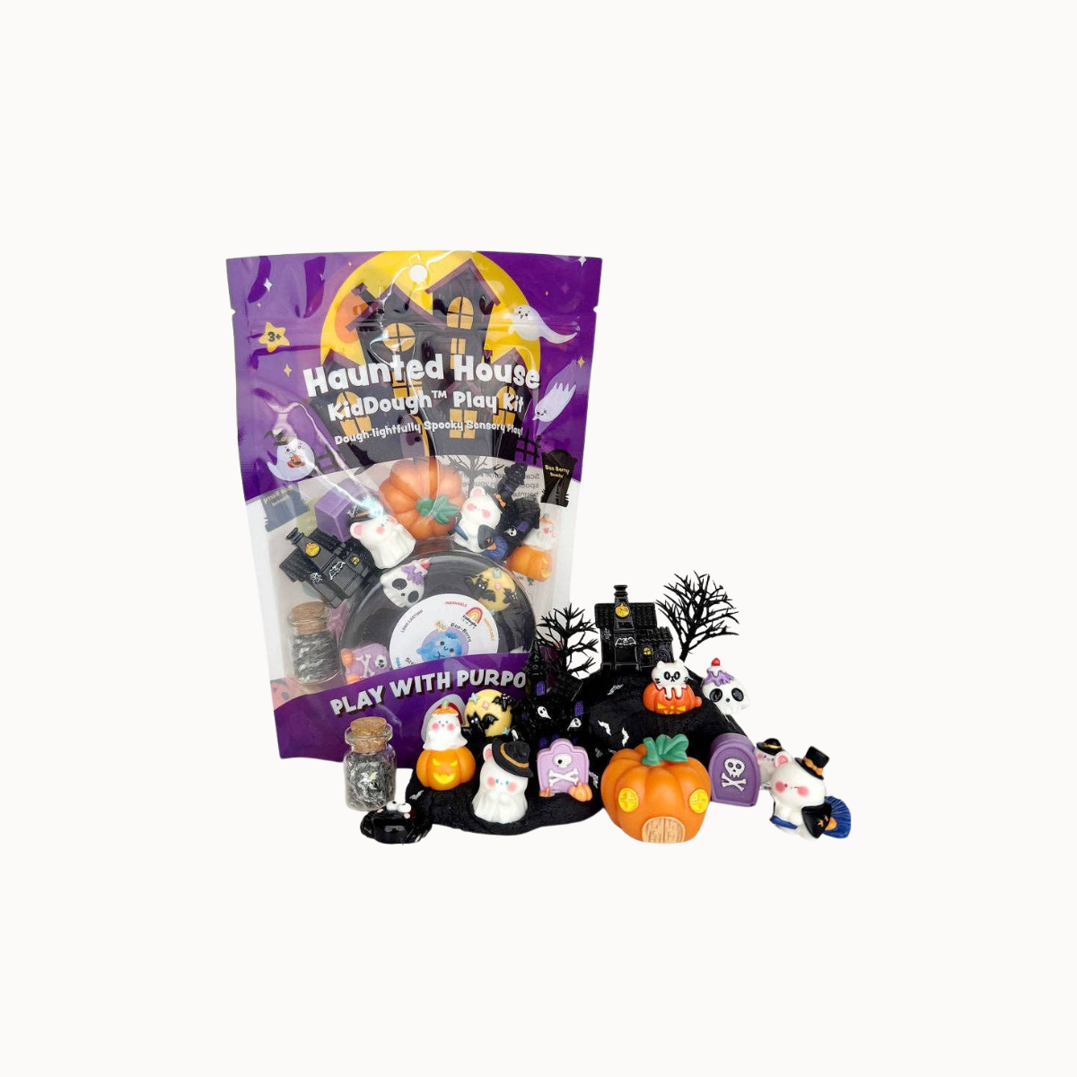 A package of 'Haunted House Play with Purpo' plastic toy figures shown next to several small Halloween-themed figurines, including a ghost, witch, skeleton, and jack-o'-lantern, on a plain white background.