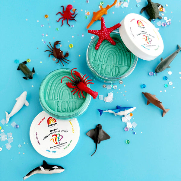 Colorful toy sea creatures with two green containers on a blue background