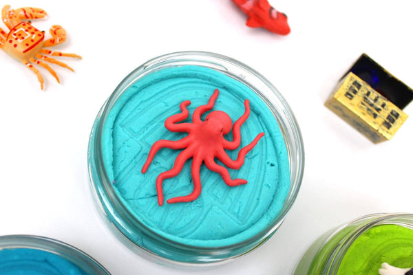 Toy octopus in a blue container with colorful toys around on a white background