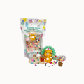 A KidDough Mini KidDough Play Pack featuring a yellow cat figure, a green hedge, a small cupcake, and colorful sprinkles, displayed next to its clear packaging bag on a white background.