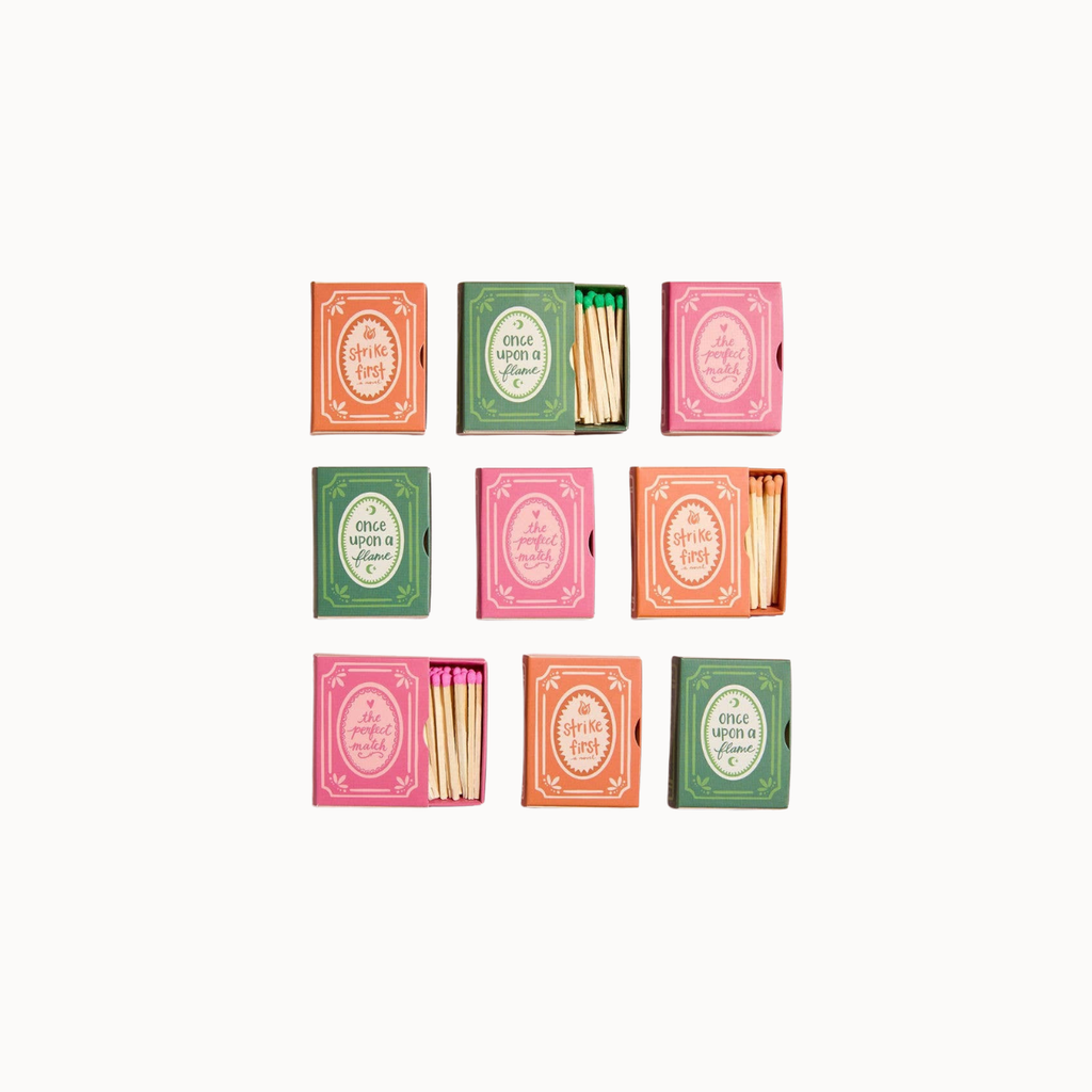 Nine colorful matchboxes arranged in a 3x3 grid on a plain white background. The matchboxes come in pink, orange, and green, and some are open to show the wooden matches inside.