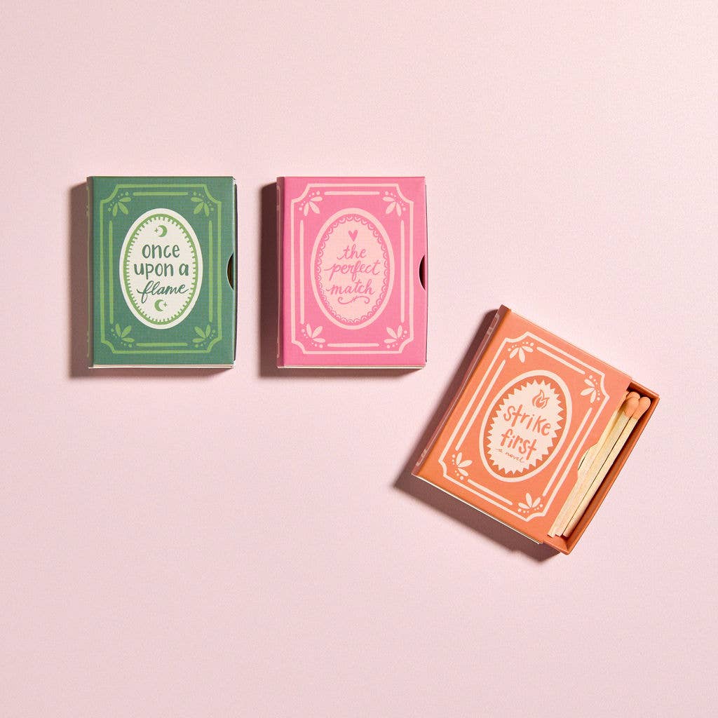 Three matchboxes with decorative labels on a pink background