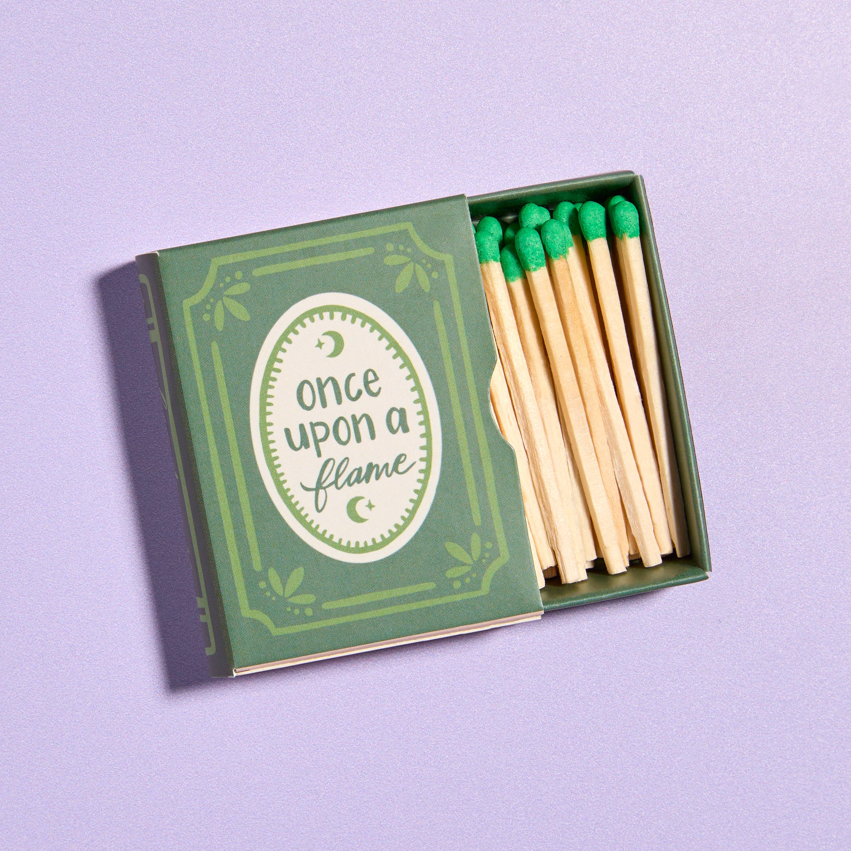 Matches with green tips in a box labeled 'Once Upon a Flame' on a purple background