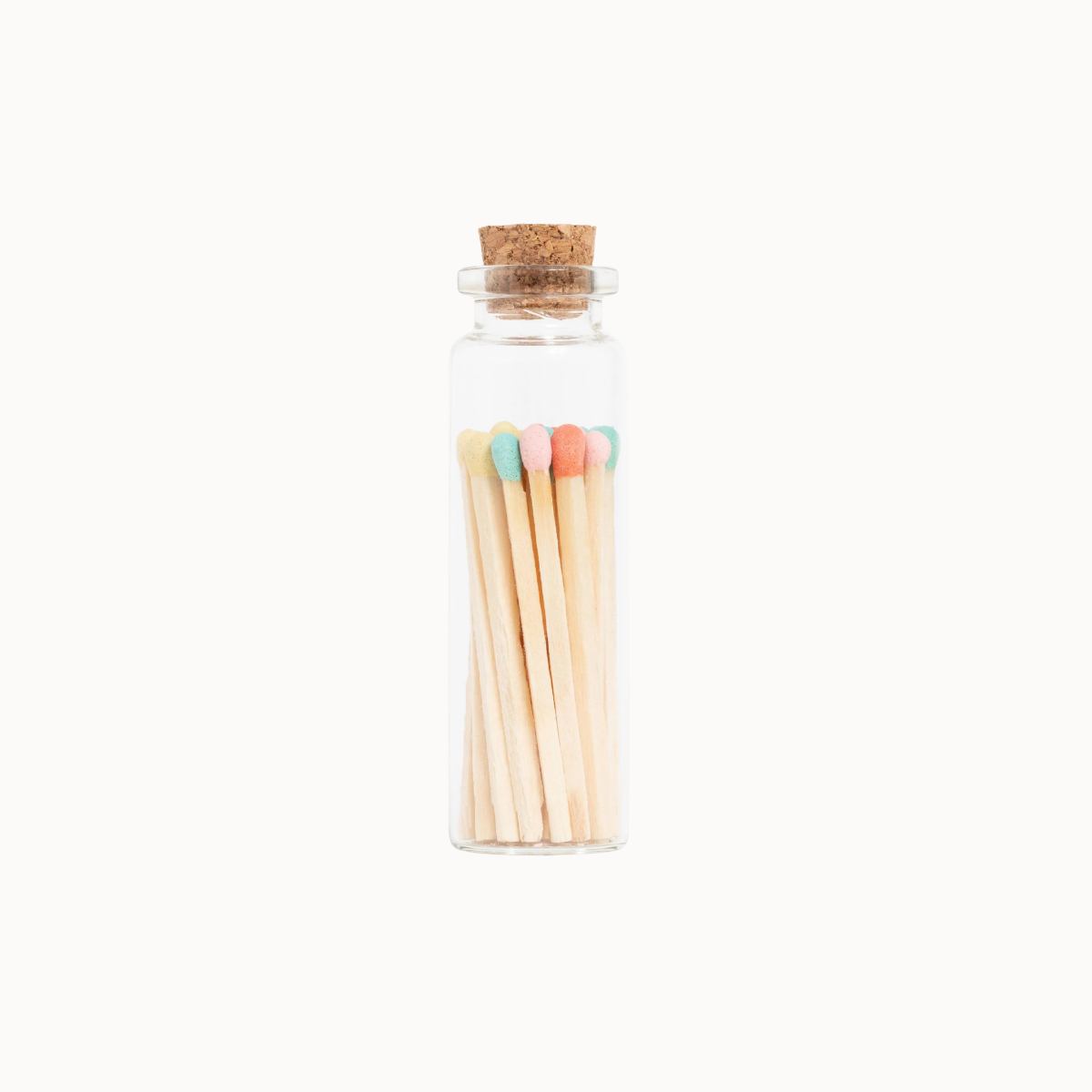 A small clear glass bottle with a cork stopper containing wooden matches with pastel-colored tips, centered on a plain white background.