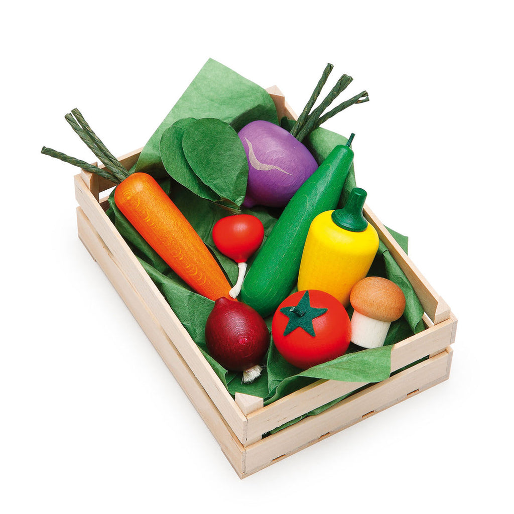 Set of colorful toy vegetables in a wooden crate on a white background