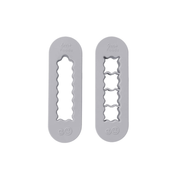 Two gray silicone food cutters designed for baby-led weaning, one for creating finger-length strips and the other for bite-sized cubes.