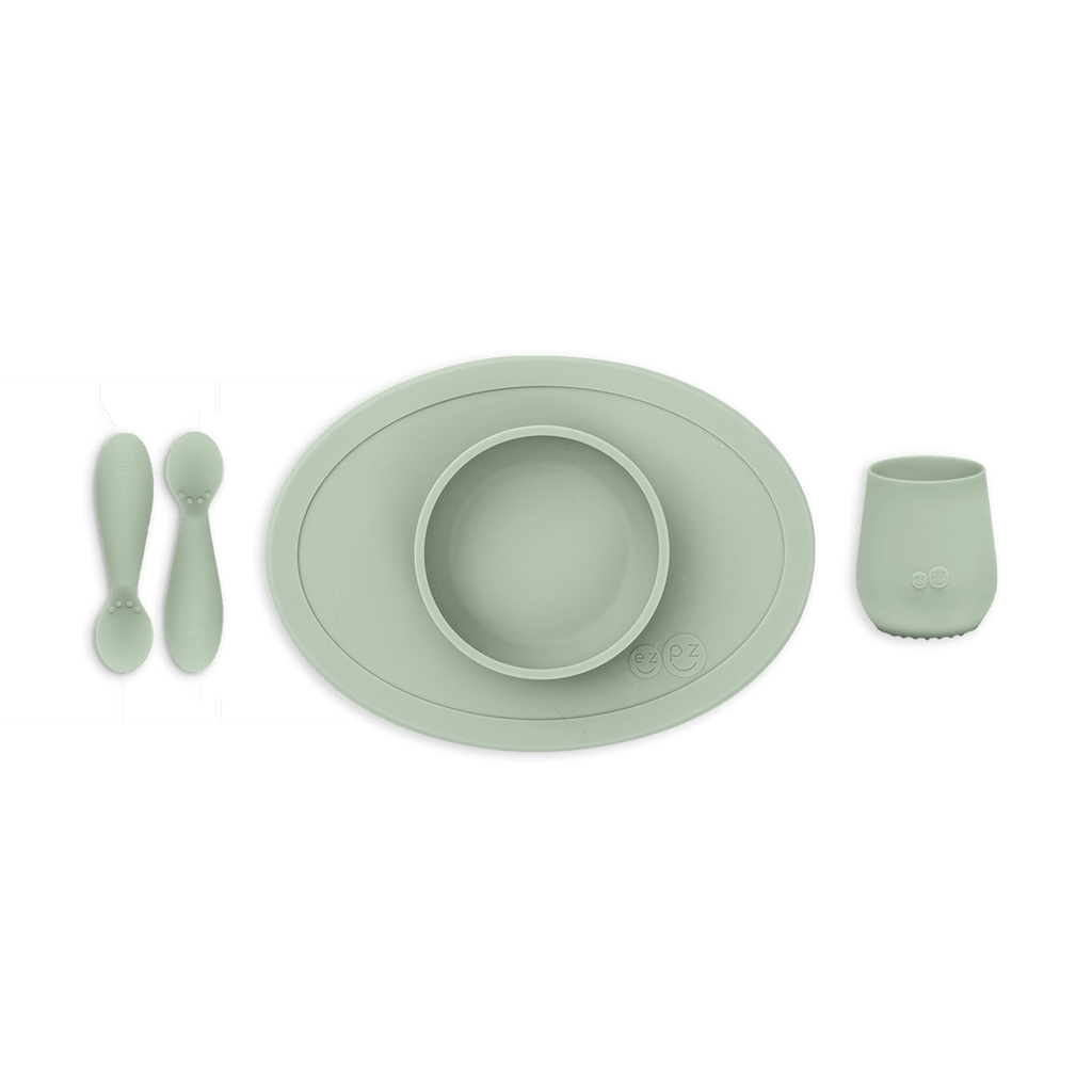 Set of green silicone utensils and placemat on a white background