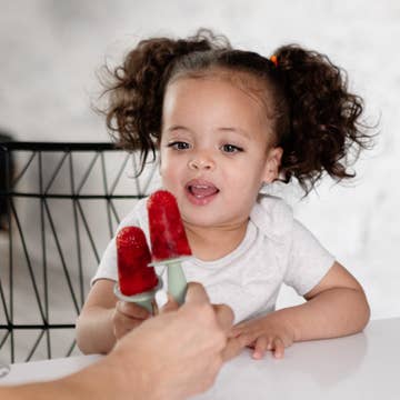 Child holding a red popsicle with a blurred background