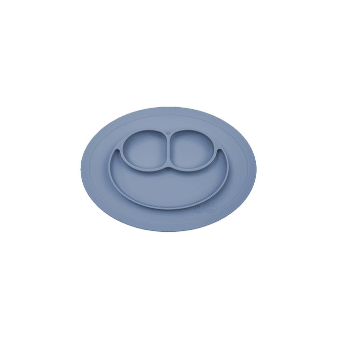 A gray ezpz Mini Mat, an all-in-one placemat and plate designed for mealtime, suctioning to a table surface.