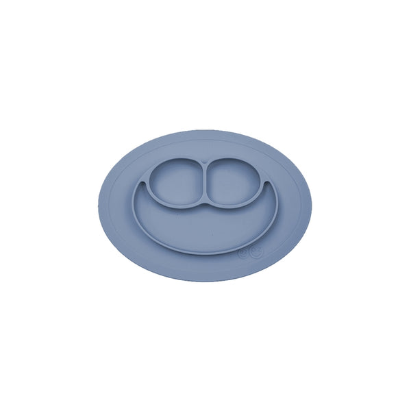 A gray ezpz Mini Mat, an all-in-one placemat and plate designed for mealtime, suctioning to a table surface.