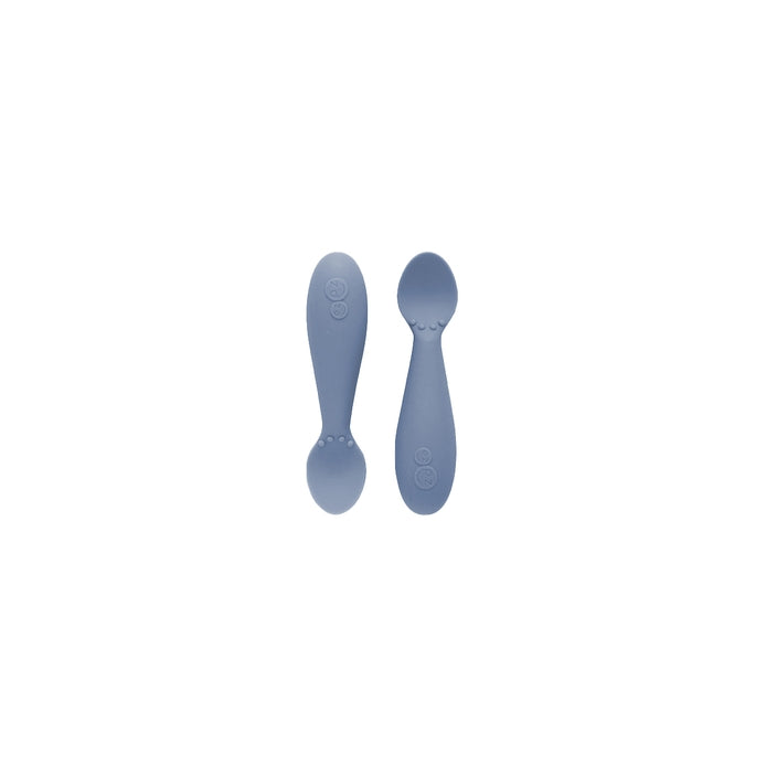 Two white silicone spoons designed for babies, with wide handles and narrow bowls.
