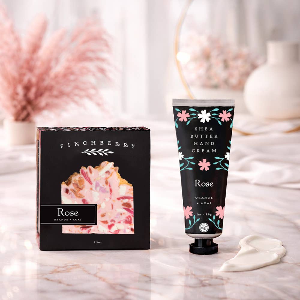 Finchberry Rose hand cream and packaging on a marble surface with decorative elements.