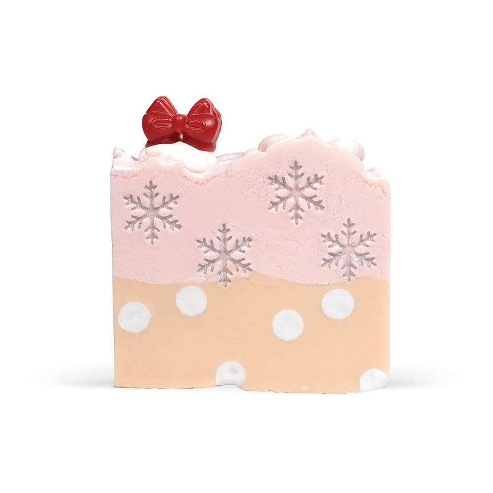 Bar of soap with pink top, beige bottom, snowflake patterns, and a red bow on a white background