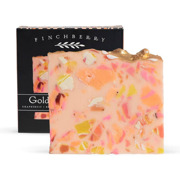 Colorful soap bar with visible ingredients next to a black Finchberry box on a white background
