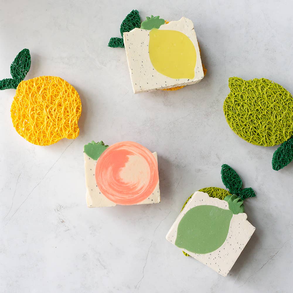Set of soap bars with fruit-shaped tops on a light gray surface