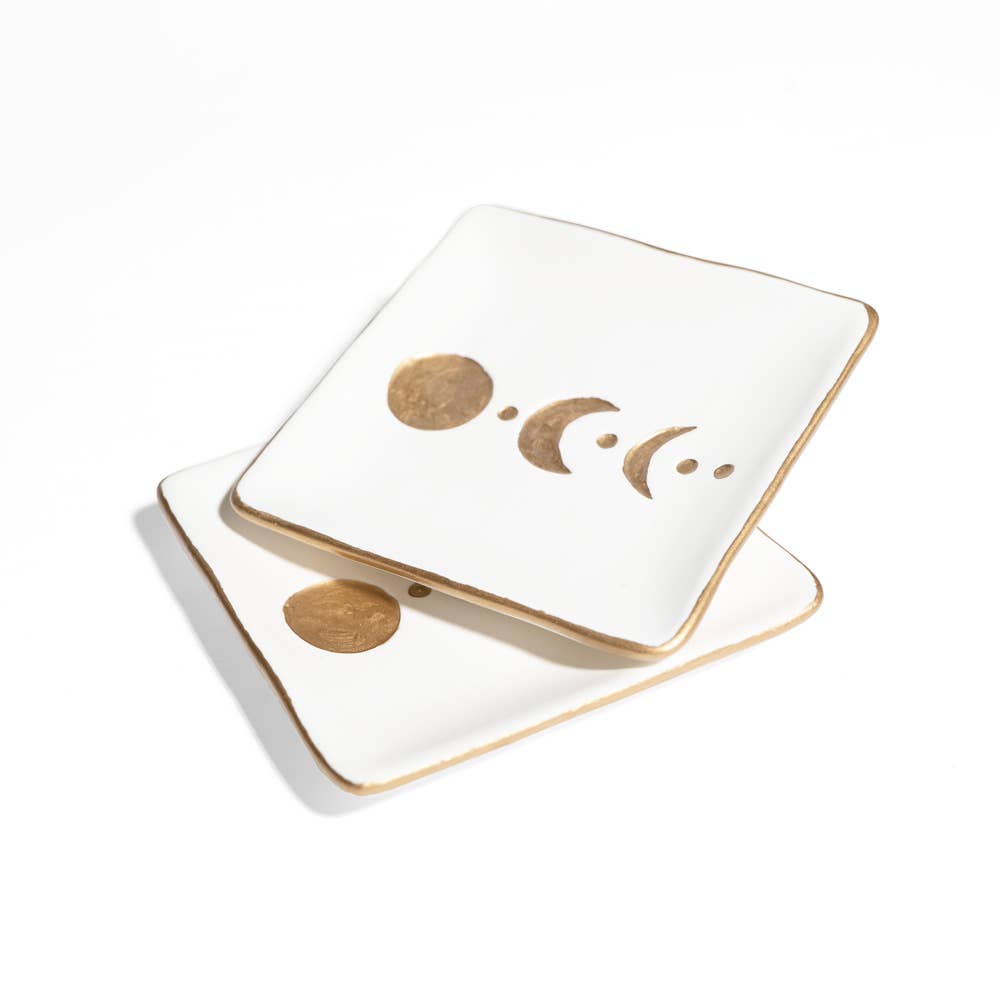 Two square white ceramic coasters with gold metallic edges and a gold moon phase design, stacked on a white background.