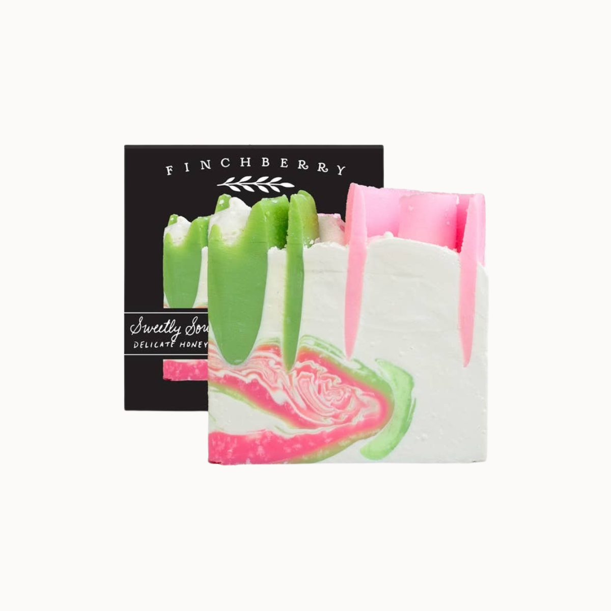 A square bar of soap with a white base and pink and green marbled swirls, shown in front of its black packaging box labeled FINCHBERRY.