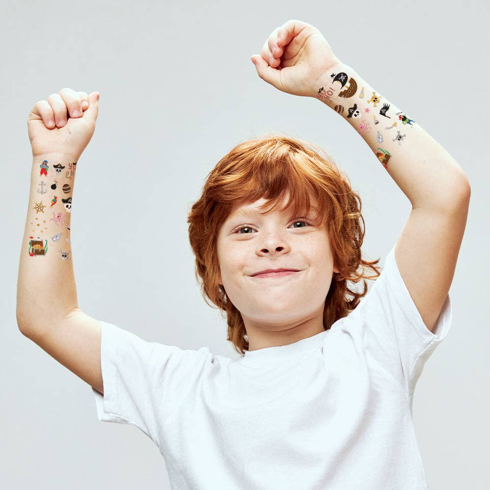 Child with temporary tattoos on arms against a plain background