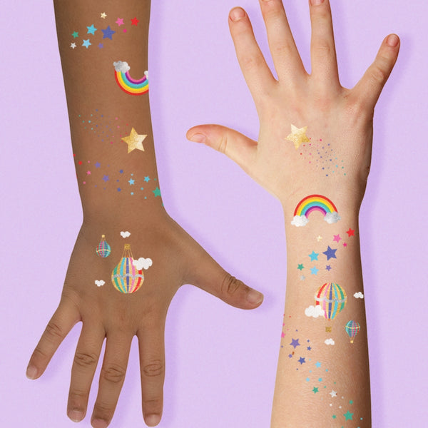 Two hands with colorful temporary tattoos on a purple background