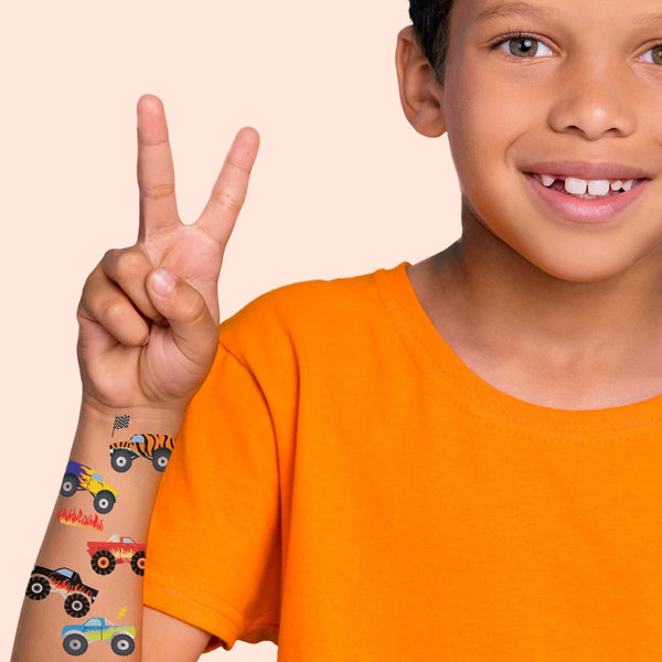 Child wearing temporary monster truck tattoos on an orange background