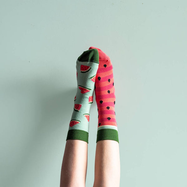 Colorful socks with watermelon design and polka dots on a light gray background