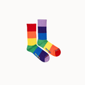 A pair of rainbow-striped crew socks with the brand name 'HUMAN SOCKS' printed in yellow on the sides, set against a plain off-white background.