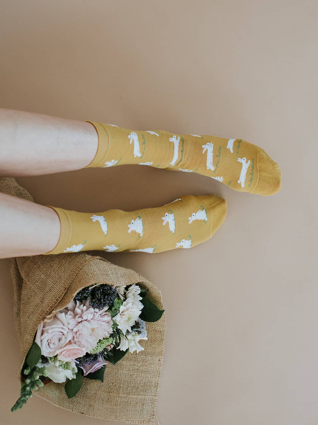 person wearing yellow bunny socks on tan background