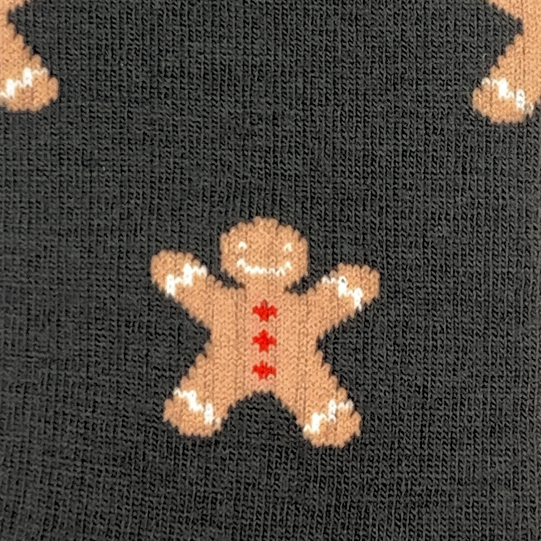 Close-up of a knitted textile pattern featuring gingerbread men motifs on a dark charcoal background.