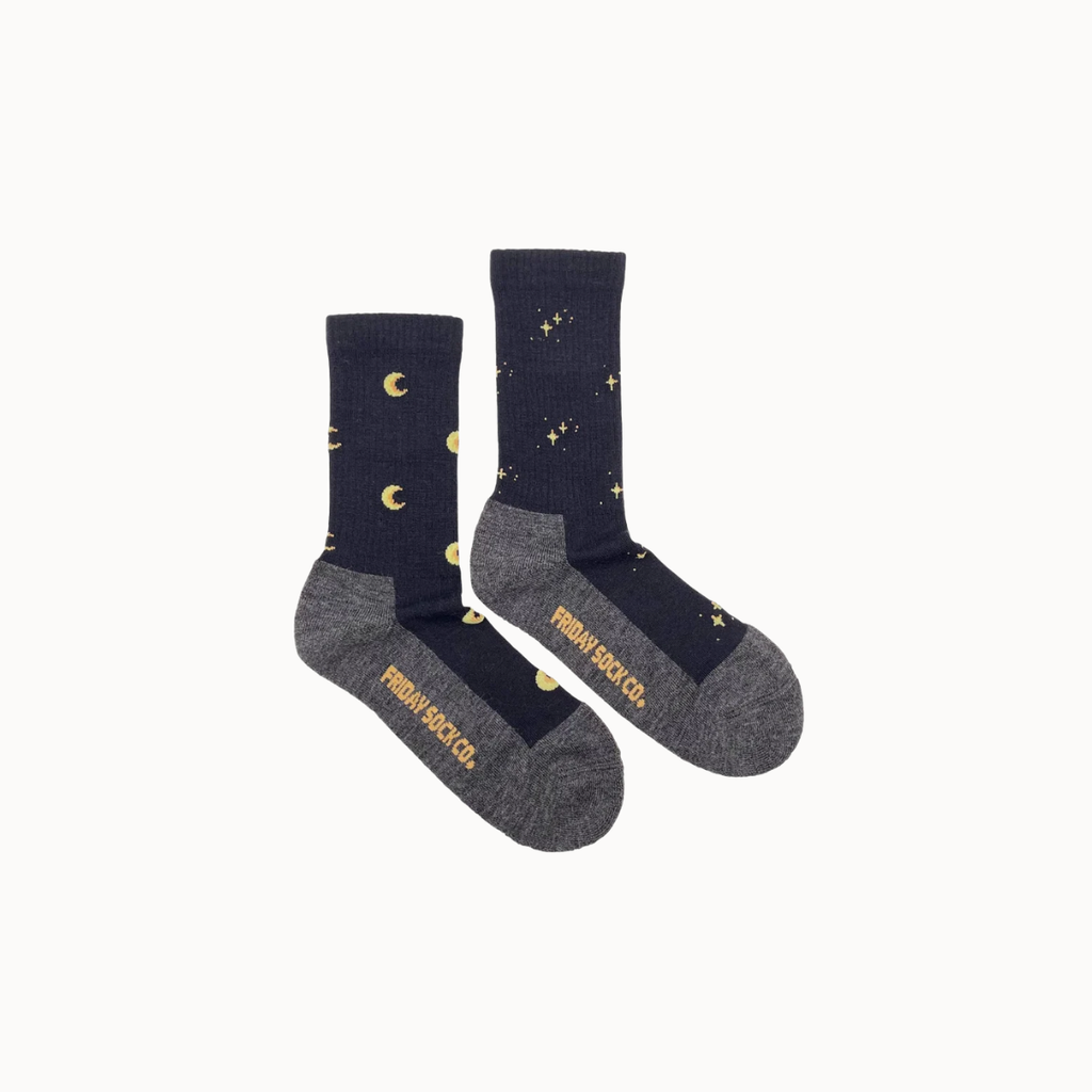 A pair of crew socks by Friday Sock Co. in navy blue and heather gray, decorated with gold crescent moons and stars, shown on a plain off-white background.