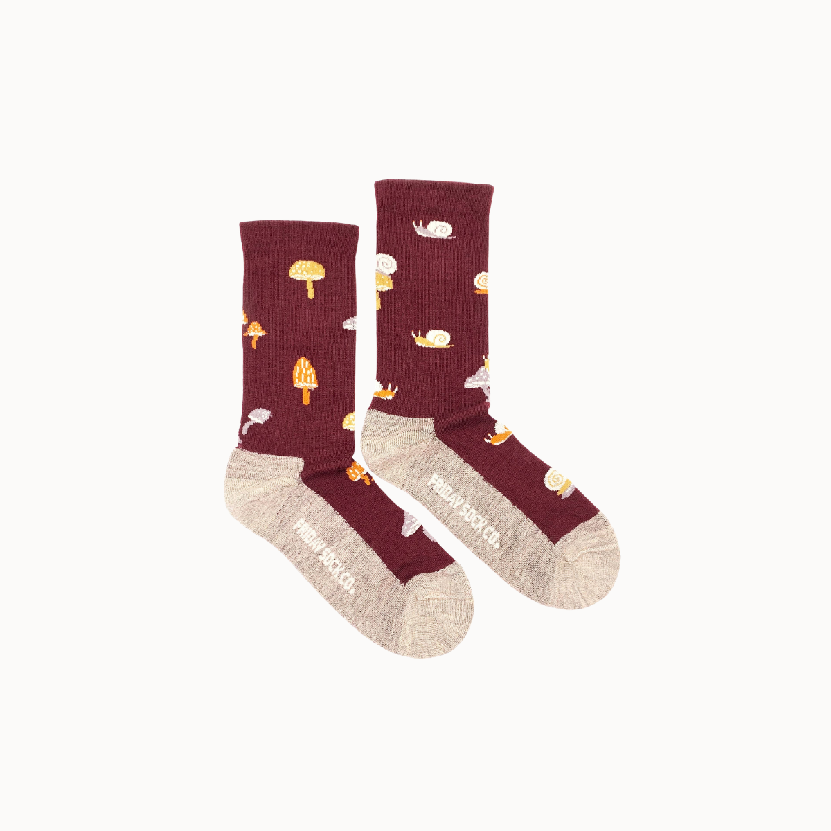 A pair of crew socks by Frökensockeln featuring a dark burgundy upper with a playful print of mushrooms, cats, and coffee cups, contrasted with a light beige knit heel, toe, and sole.