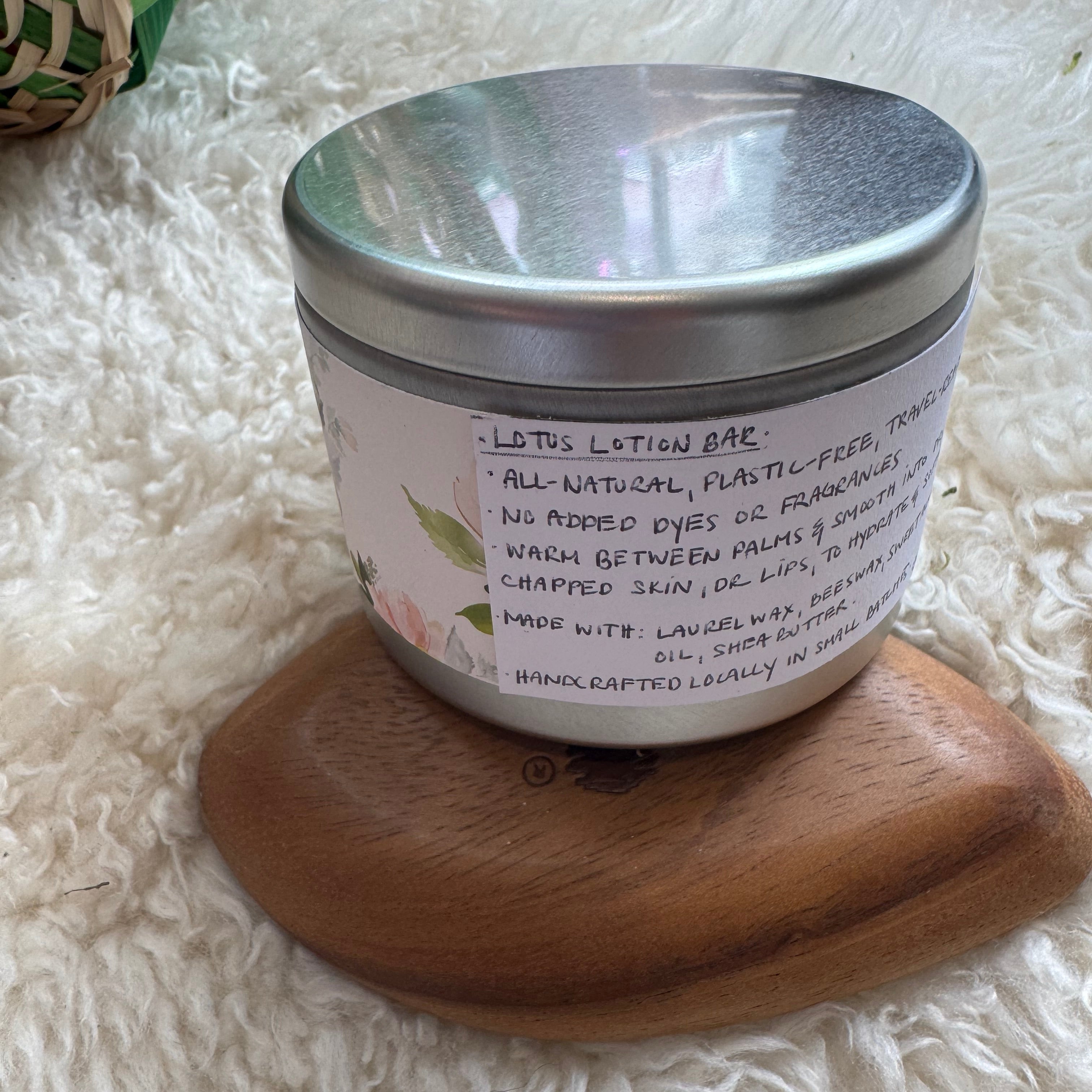 Lotion bar in a wooden holder with a metal lid on a fluffy white surface