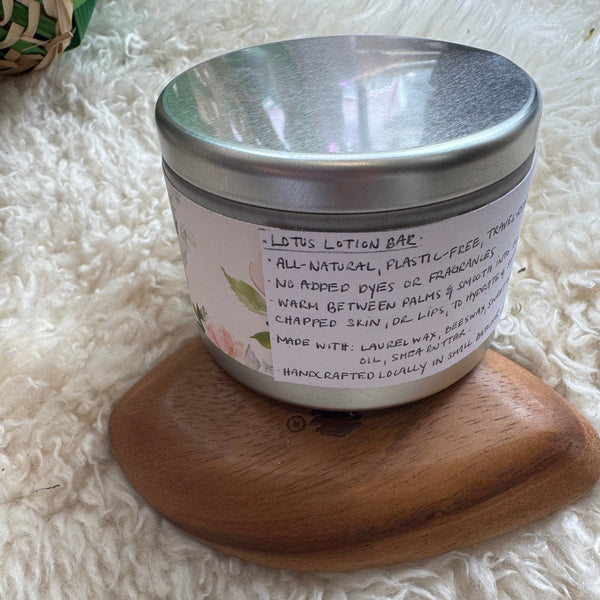 Lotion bar in a wooden holder with a metal lid on a fluffy white surface