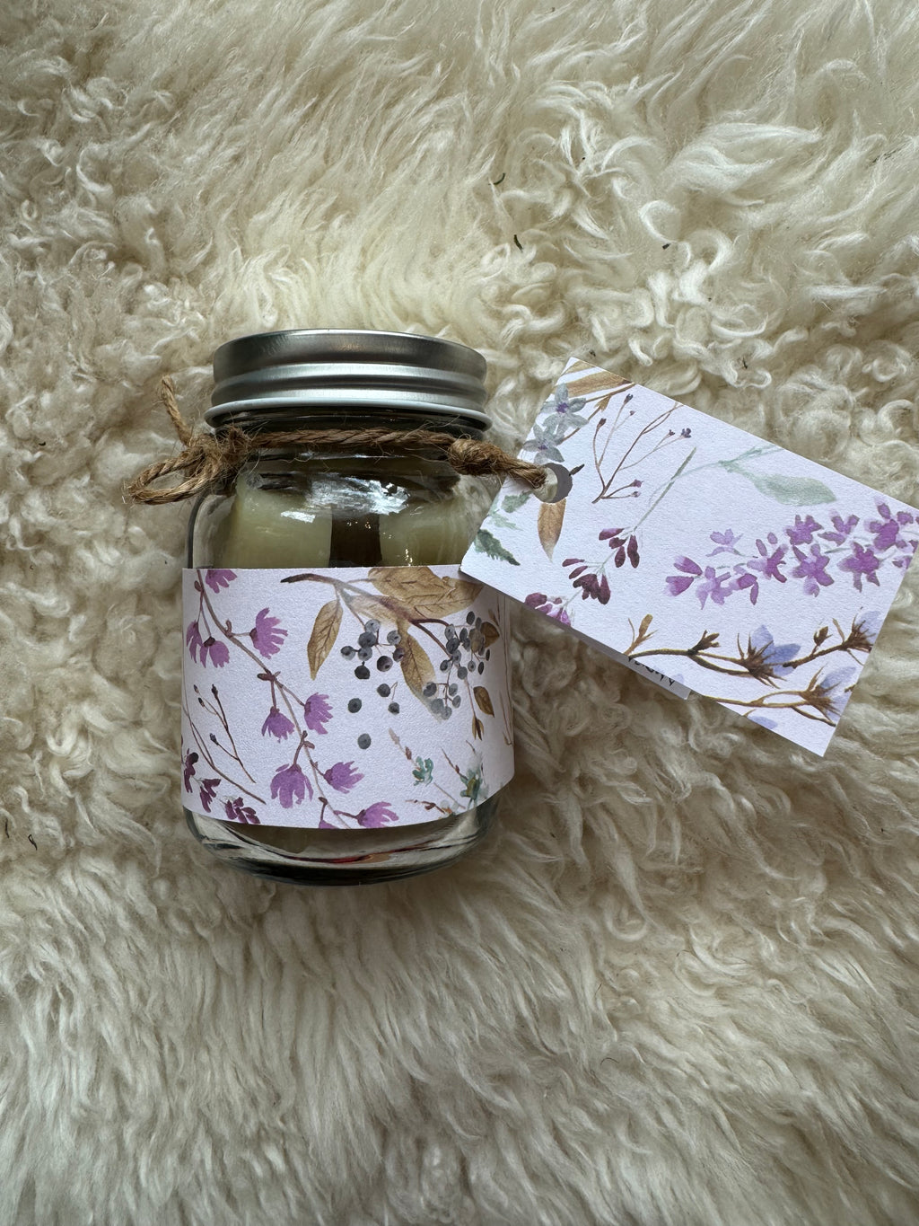 Small glass jar with floral ribbon on a fluffy white surface