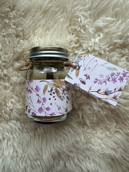 Small glass jar with floral ribbon on a fluffy white surface