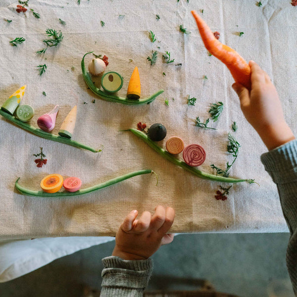 Hand arranging small vegetables on a textured surface