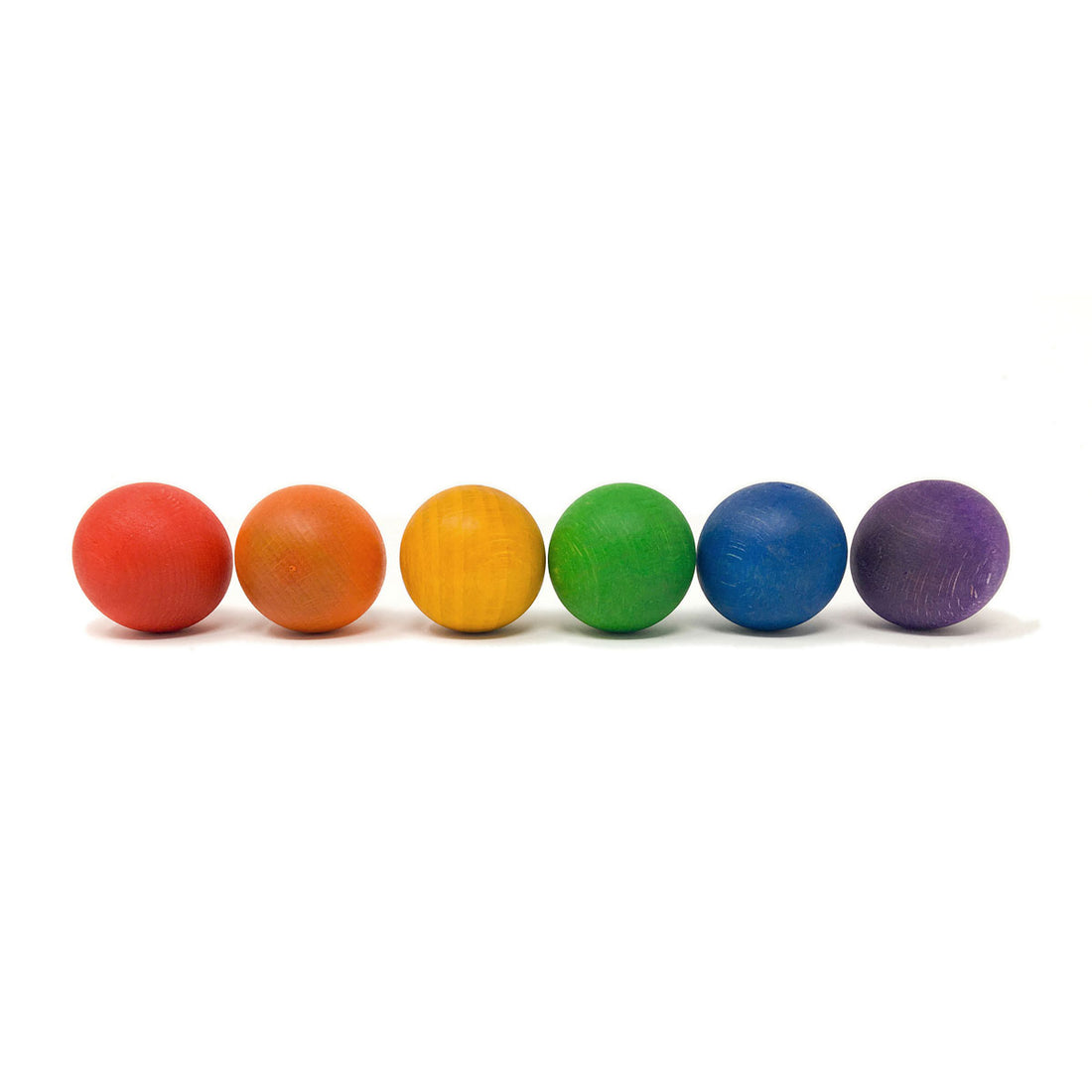 Six small painted wooden balls in a rainbow color sequence, arranged in a row on a plain white background.
