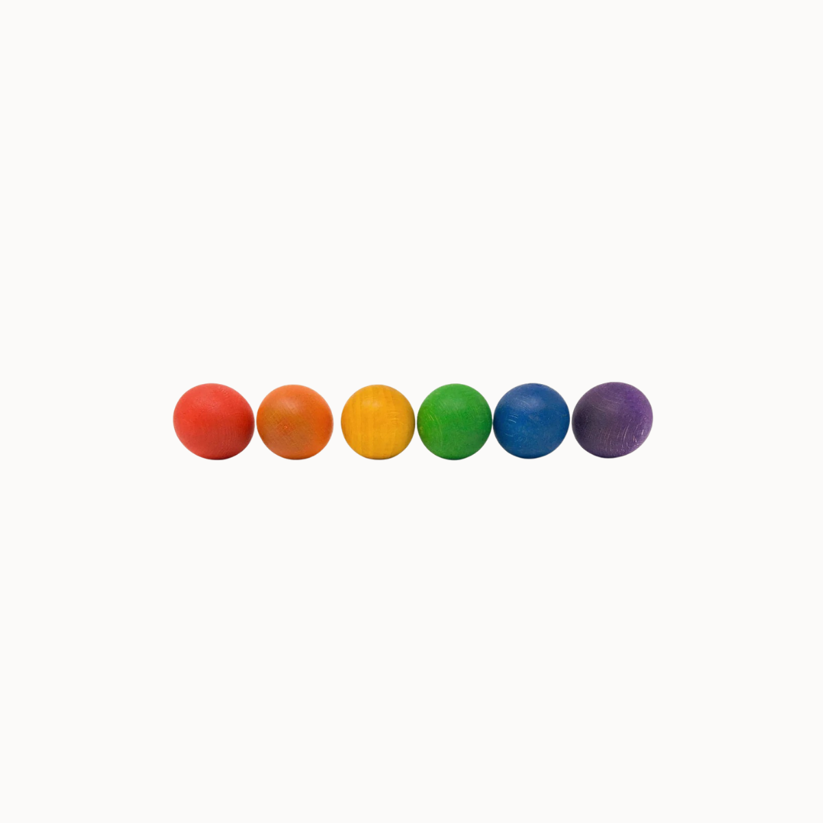 Six small round balls in a row, colored red, orange, yellow, green, blue, and purple, centered on a plain white background.