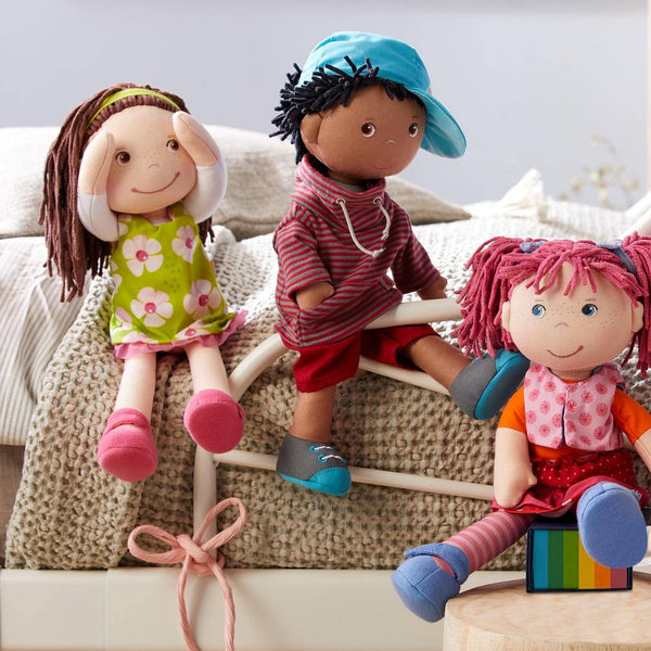 Three dolls on a couch with a neutral background