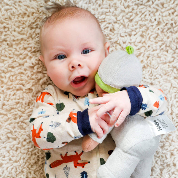Baby lying on a carpeted floor holding a soft toy