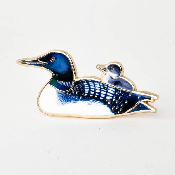 Enamel pin of a blue loon bird on a white background