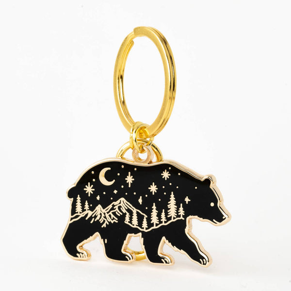 Gold hoop earring with a black bear charm featuring a night sky design on a white background