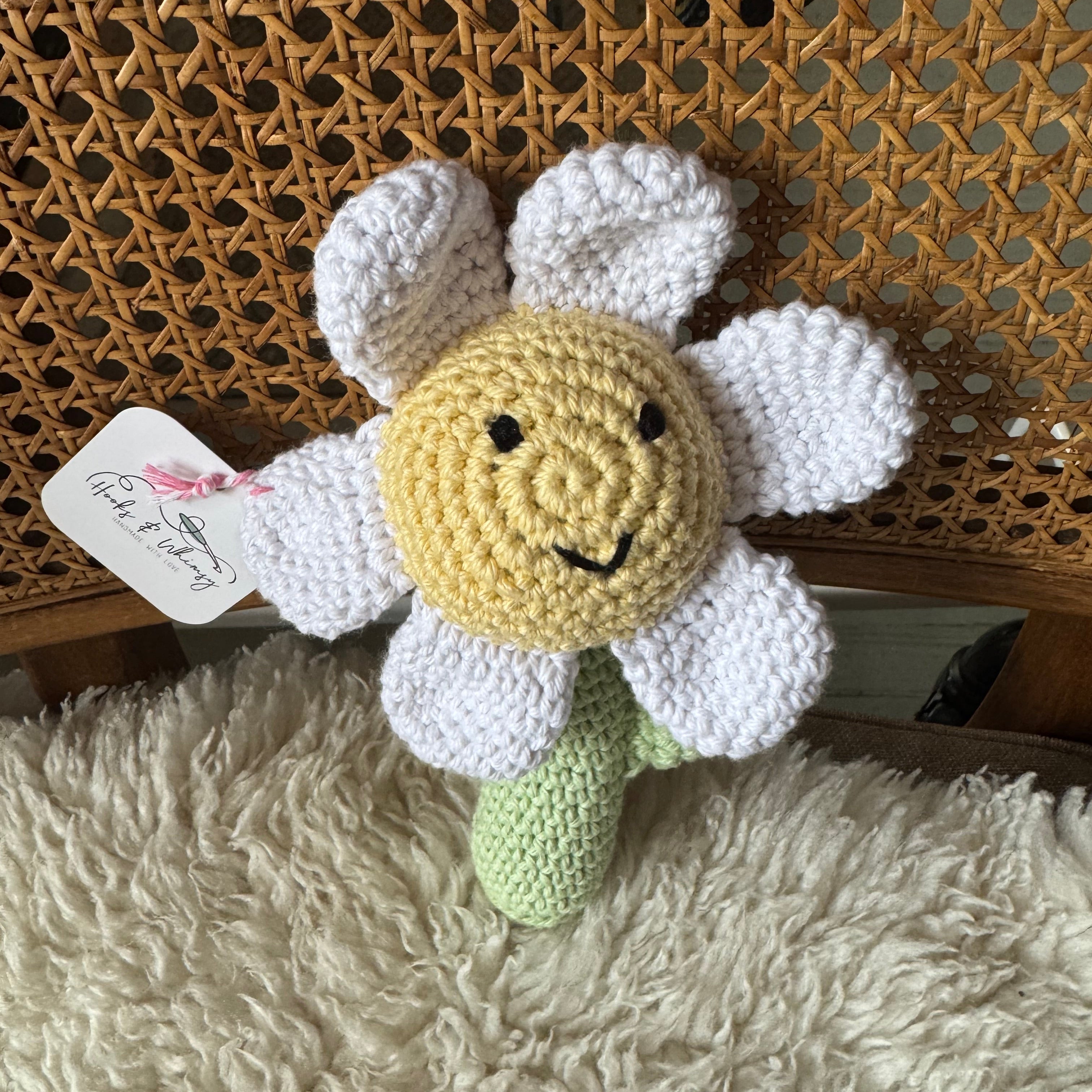 Crocheted flower-shaped toy with a tag on a textured surface