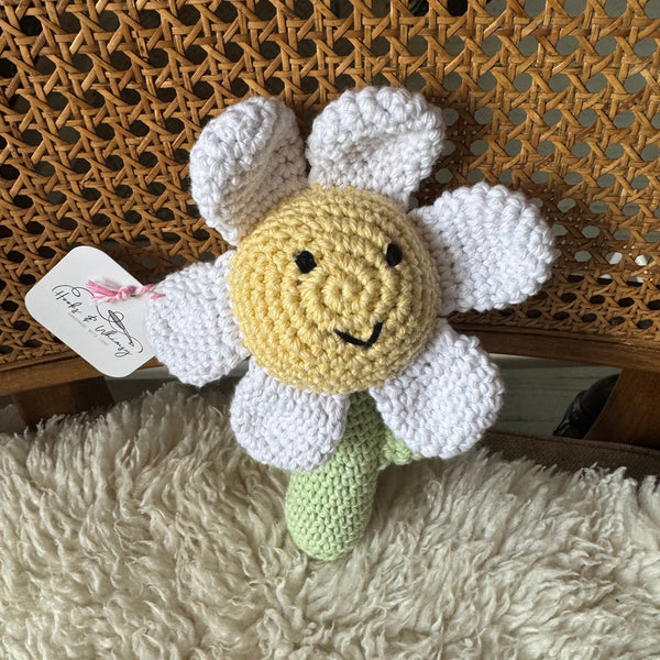 Crocheted flower-shaped toy with a tag on a textured surface